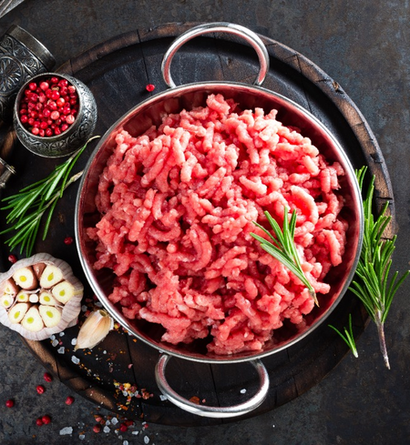 Grass-fed ground beef from Champion Valley Farm in a bowl with fresh herbs and garlic