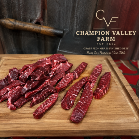 Sliced grass-fed beef fajita meat on a cutting board with Champion Valley Farm branding